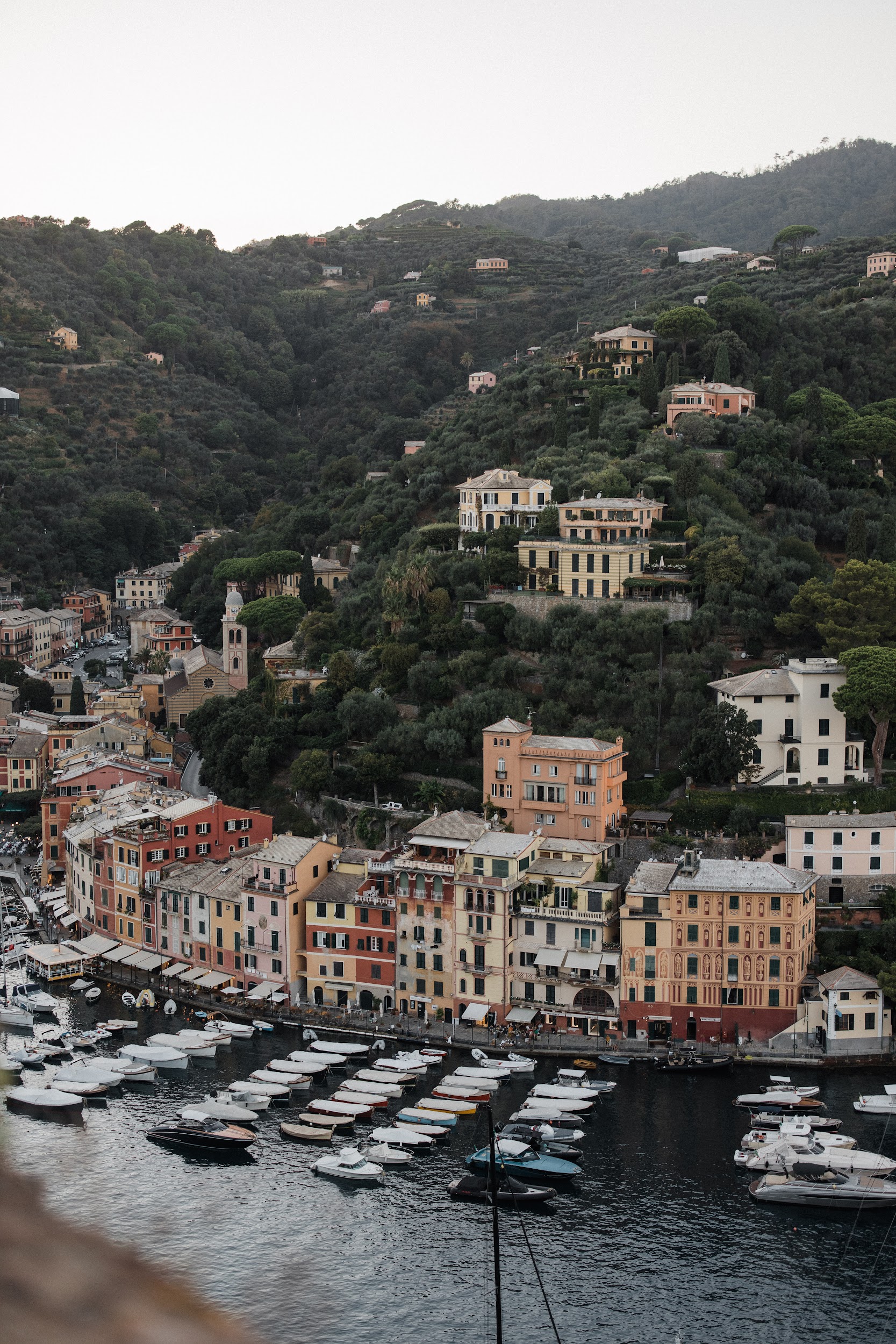 wedding-in-portofino (50) A coastal village with colorful buildings along the waterfront, boats docked in the harbor, and houses scattered on a green hillside—an idyllic setting perfect for a wedding planner Liguria Italy dreams of.