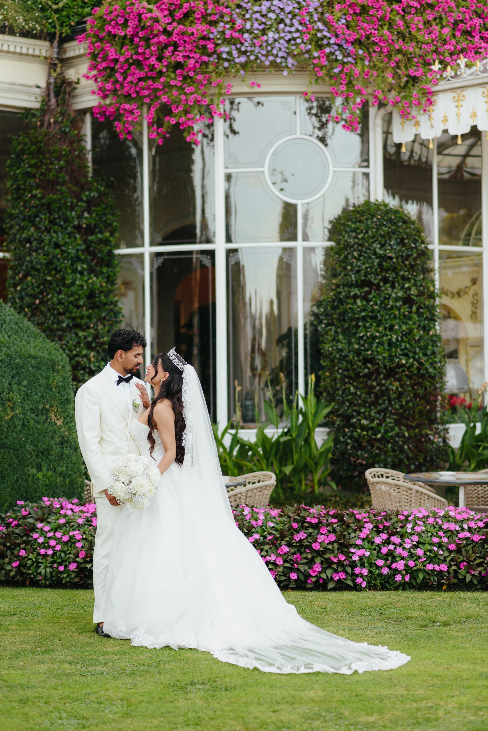 Bride and groom holding hands in a romantic garden with pink flowers in Stresa, Italy.