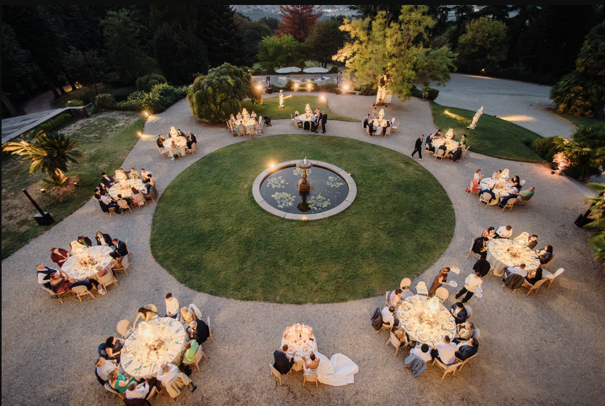 Outdoor Wedding Reception at Villa Cimena | Turin, Italy Aerial view of Enrico and Giannella's outdoor wedding reception at Villa Cimena in Turin, with elegant round tables arranged around a central fountain at sunset.