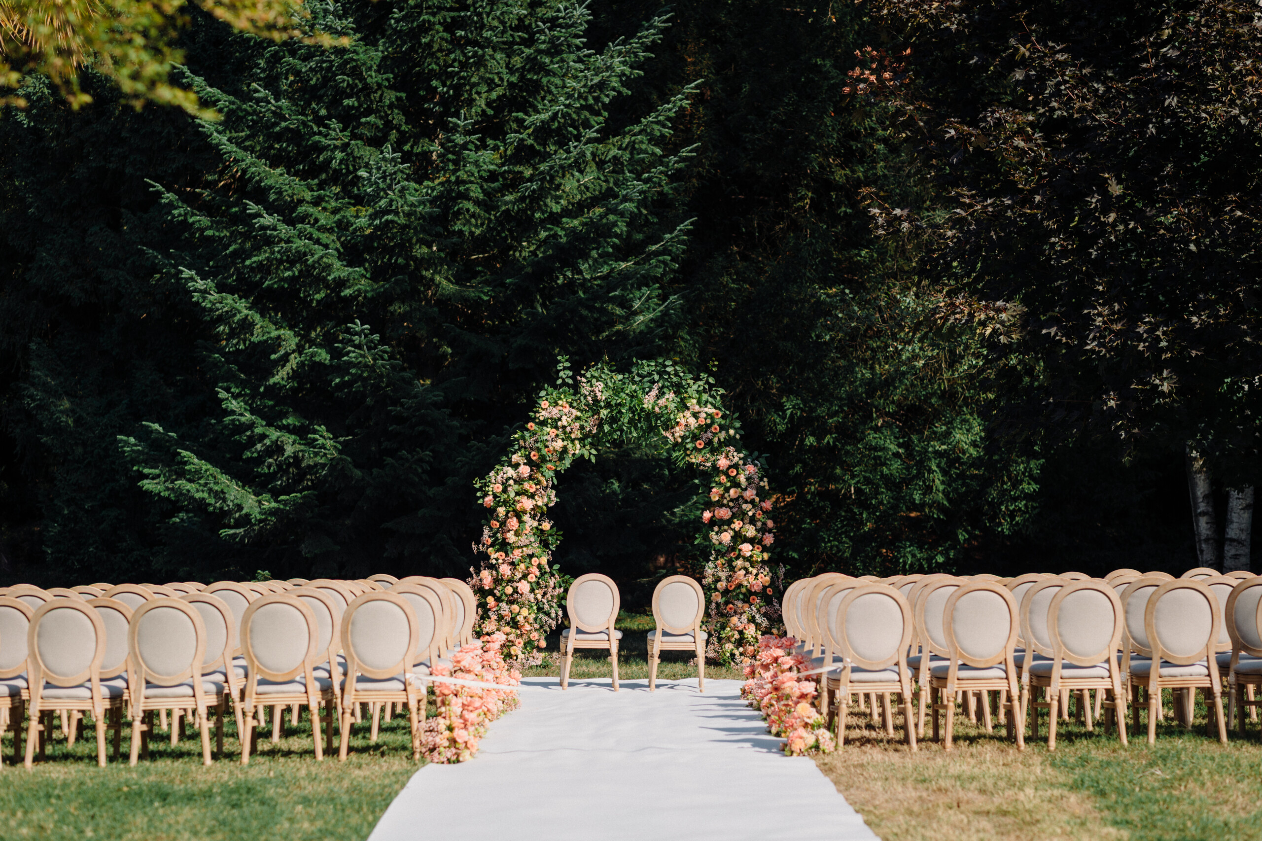Outdoor Wedding Ceremony Setup at Villa Cimena Elegant white wedding aisle with classic chairs and pink floral arrangements for an outdoor ceremony at Villa Cimena.