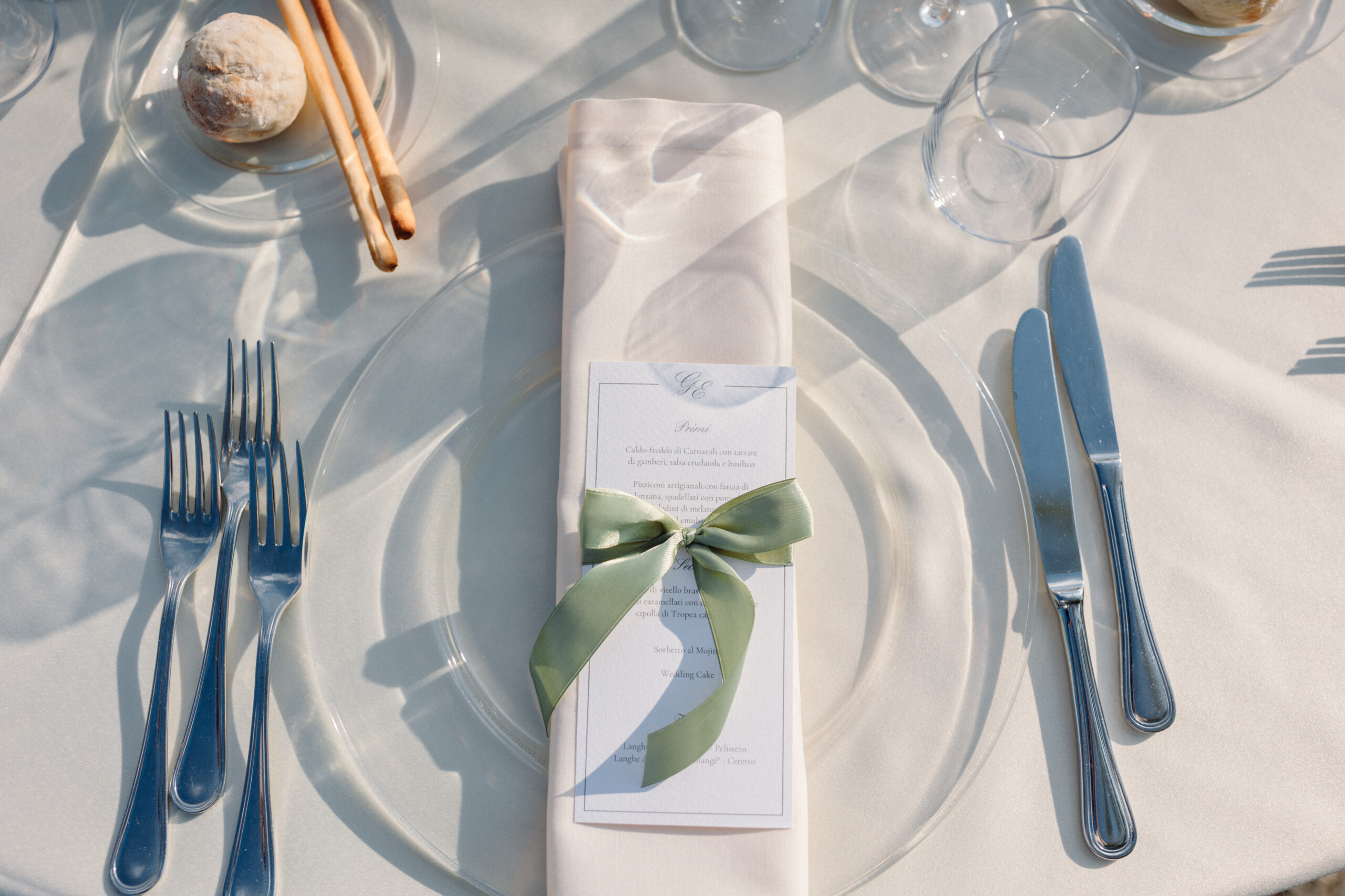 Wedding Menu and Table Setting – Villa Cimena Personalized wedding menu tied with a sage green ribbon on a white plate at Villa Cimena in Turin.