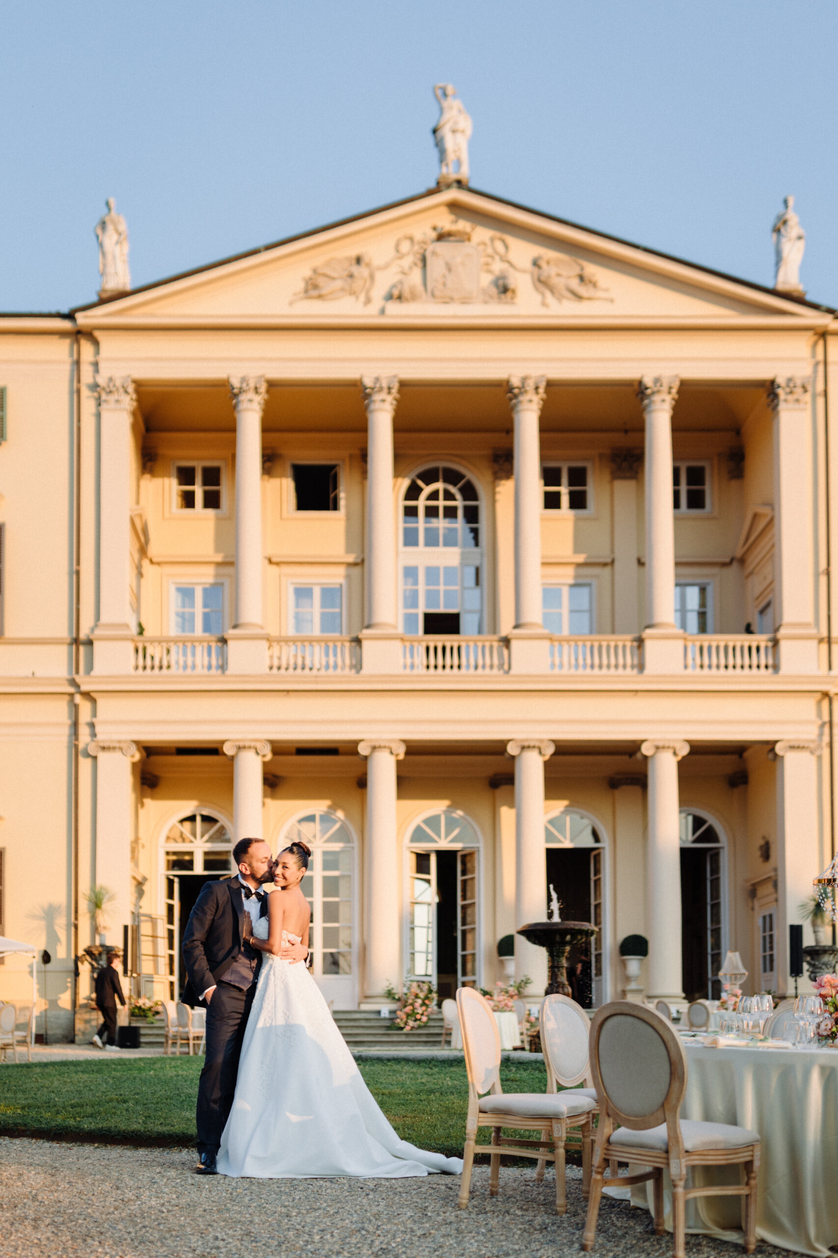 Elegant Wedding at Villa Cimena – Giannella and Enrico Giannella and Enrico embracing in front of the neoclassical facade of Villa Cimena, with elegant outdoor wedding reception tables.