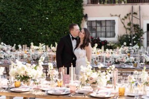 Matrimonio in Piemonte - la Villa, bacio tra gli sposi immersi nei tavoli del ricevimento, decorati con fiori dai toni delicati e candele.