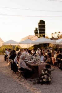 Matrimonio in Piemonte - la Villa, momento della cena all'aperto con tavoli in legno e fiori dai toni delicati, luci decorative e atmosfera familiare e rilassata.
