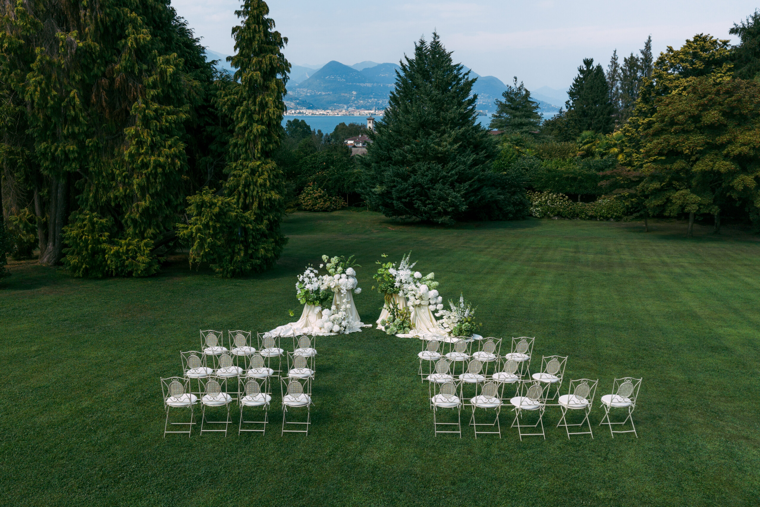 Matrimonio sul Lago Maggiore a Villa Muggia Allestimento della cerimonia nel giardino panoramico con sedute bianche e vista sul Lago Maggiore.