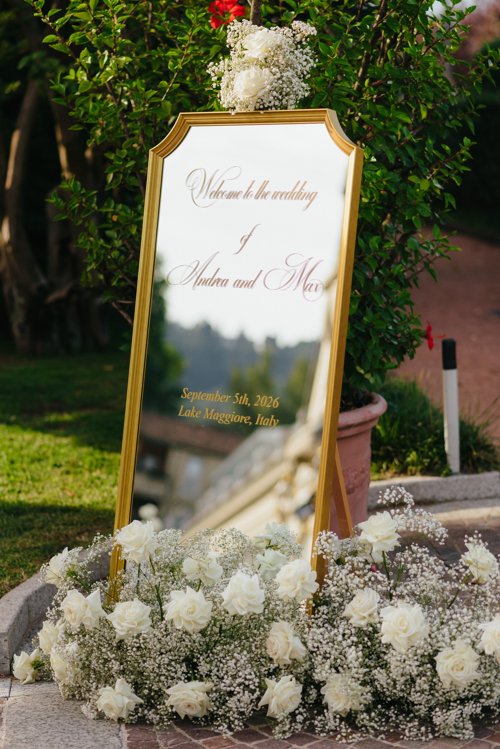 Cartello di benvenuto matrimonio sul Lago Maggiore Cartello di benvenuto per matrimonio con specchio dorato, rose bianche e decorazioni floreali sul Lago Maggiore.