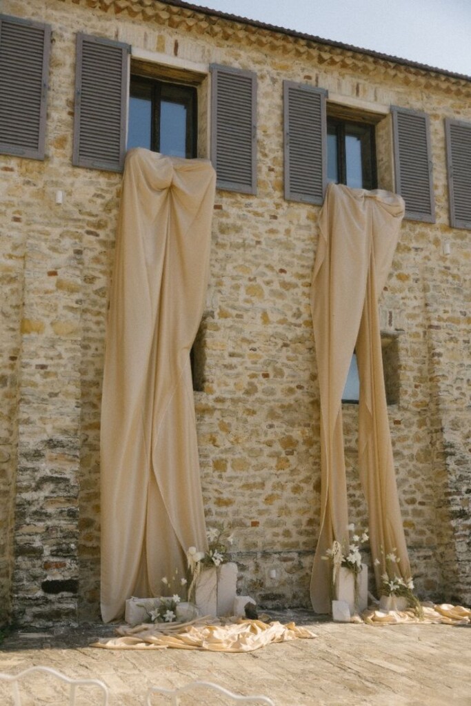 Drappeggi color champagne su una facciata in pietra per l'allestimento di una cerimonia di matrimonio