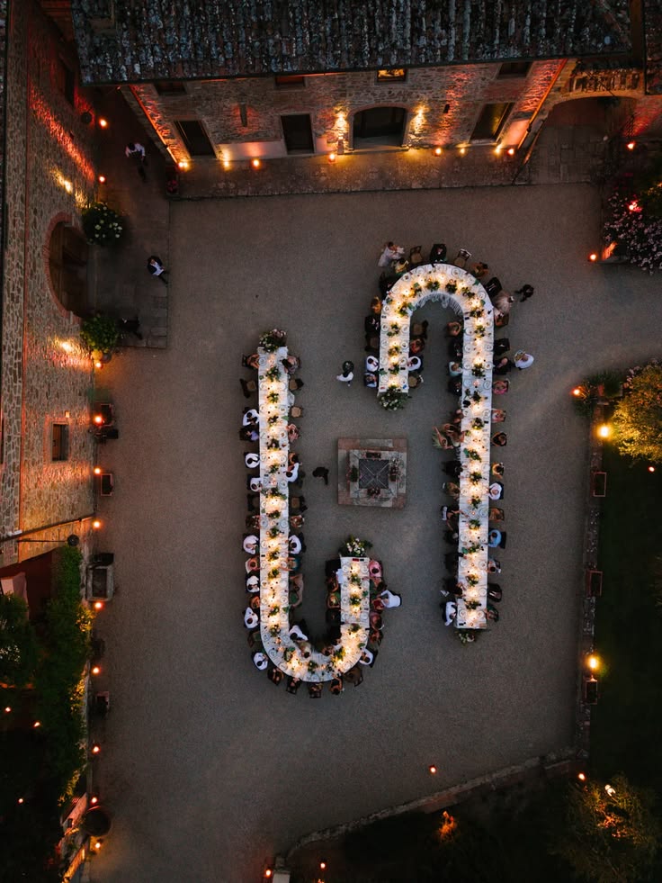 Tavolo serpentina per ricevimento di matrimonio serale, visto dall'alto, con decorazioni e illuminazione calda.